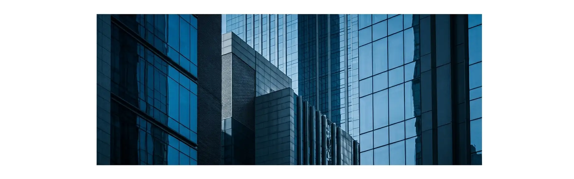 Vista de prédios comerciais altos com fachadas de vidro e estrutura metálica em ambiente urbano, com reflexos do céu e perspectiva em ângulo baixo.